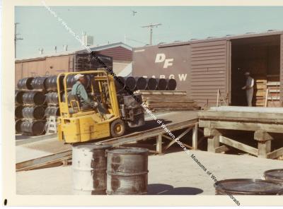 Hyster operator carrying two drums up ramp for loading in freight car