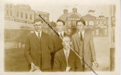 4 Men In Front Of Painted Backdrop Of A Town