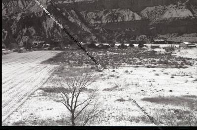 B&W photo of possible home or ranch in winter with several buildings and field.