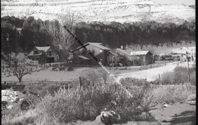 B&W photo of the Goffredi Ranch in winter with several buildings, fencing at base of mountain.