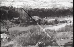 B&W photo of the Goffredi Ranch in winter with several buildings, fencing at base of mountain.