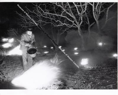 Photo of individual next to small controlled fires