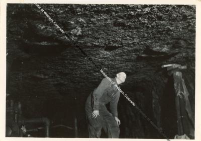  Photograph of a miner looking up at the roof of the mine