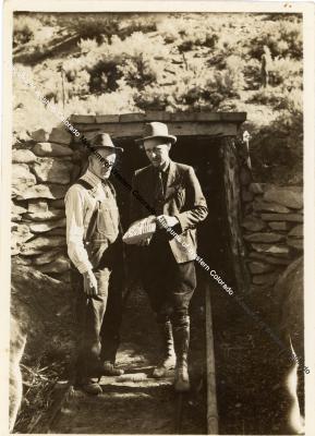 Photo of two men standing at the entrance of the mine with fossil
