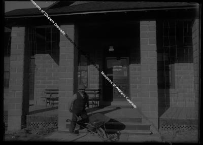 Man with wheelbarrow in front of the Uintah office 